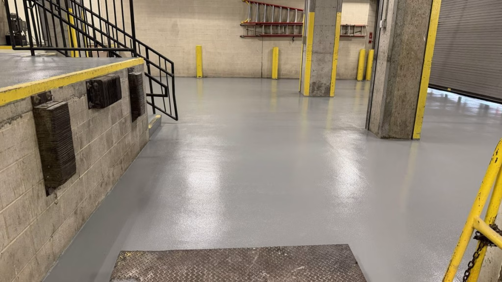 Heavy-duty industrial epoxy flooring installed in a warehouse with forklift traffic and safety pillars