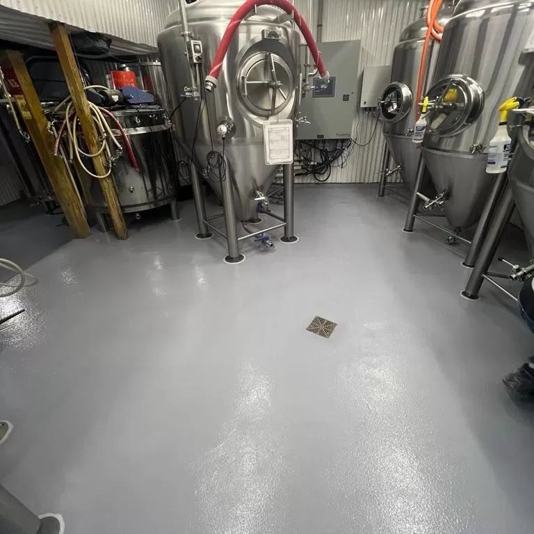 Installing high-traction non slip commercial kitchen flooring for safety and USDA compliance in a food processing facility.