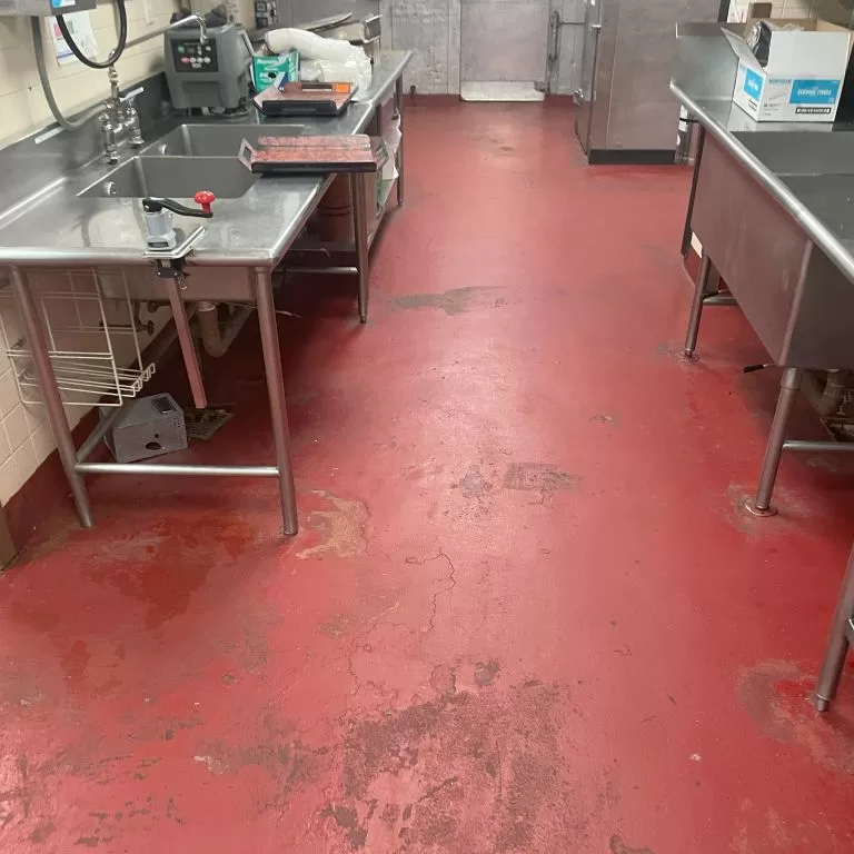 Commercial kitchen floor preparation by High Performance Systems, showing the initial state before applying USDA-compliant coatings.