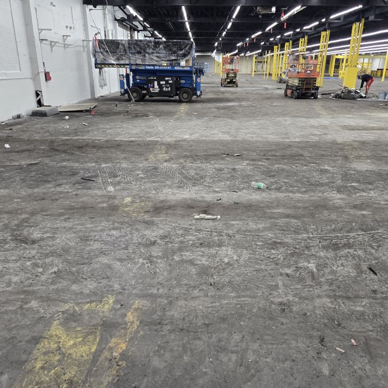 Unprepared, cracked concrete warehouse floor before industrial epoxy flooring installation in a Central Jersey logistics facility.