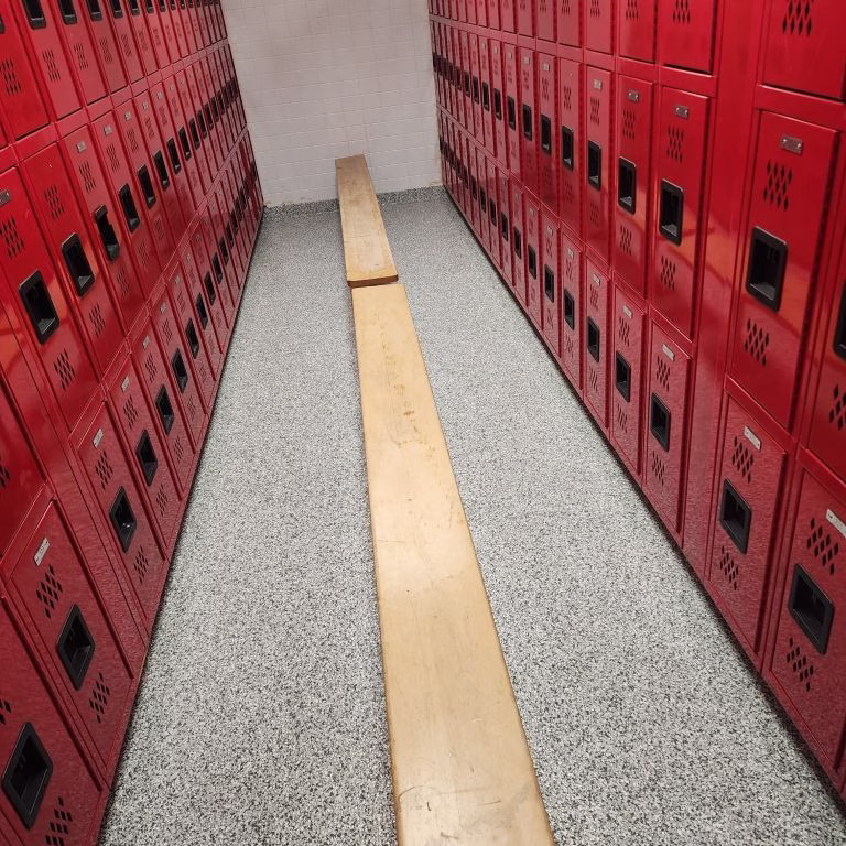 Commercial epoxy flake flooring installed in a New Jersey school or gym locker room facility with red lockers.