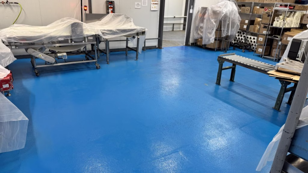 Heavy-duty red urethane cement flooring meeting USDA Compliant Commercial Kitchen Flooring around stainless steel equipment mounts in a food zone.